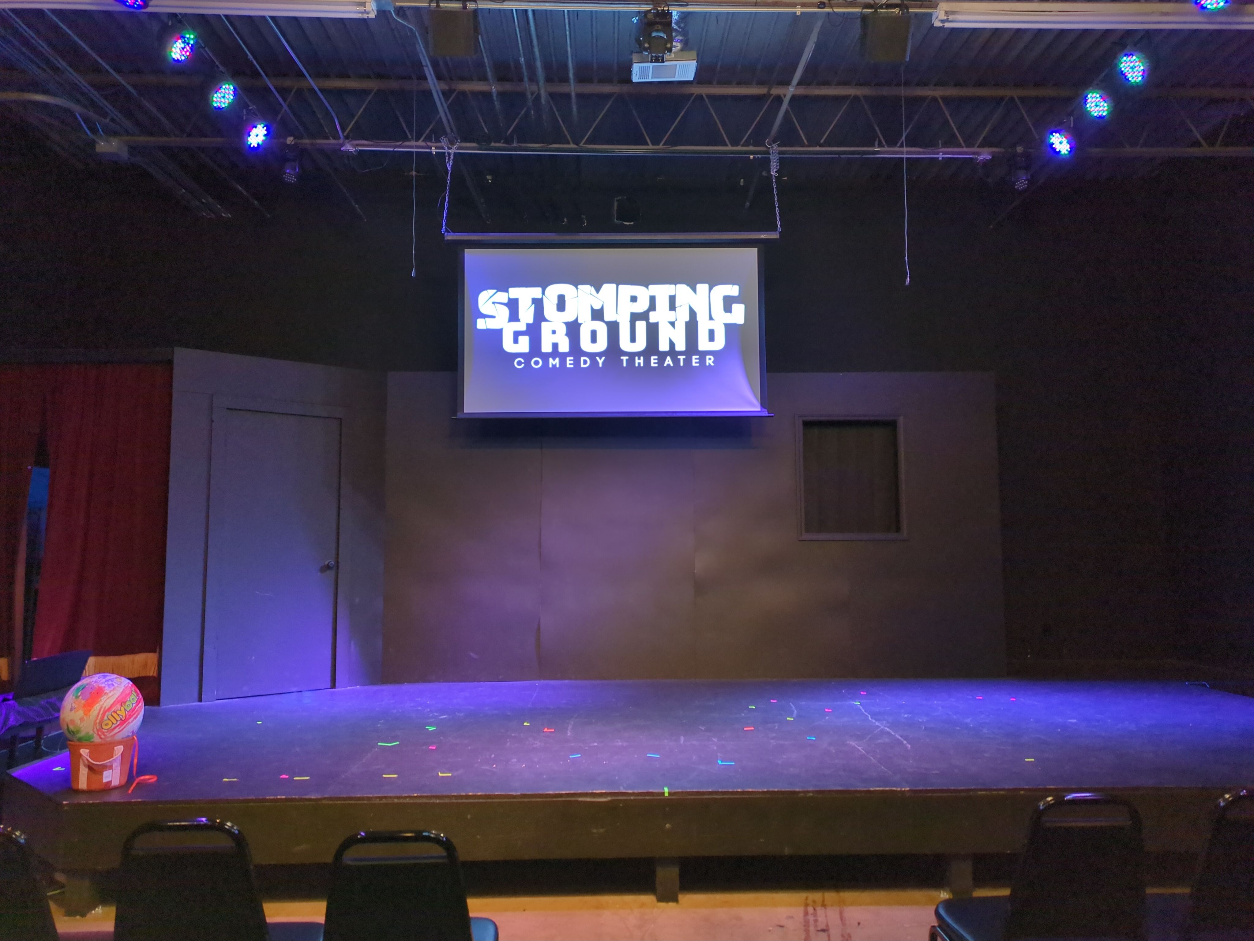 An empty theater stage with a colorful ball sits at the front edge.