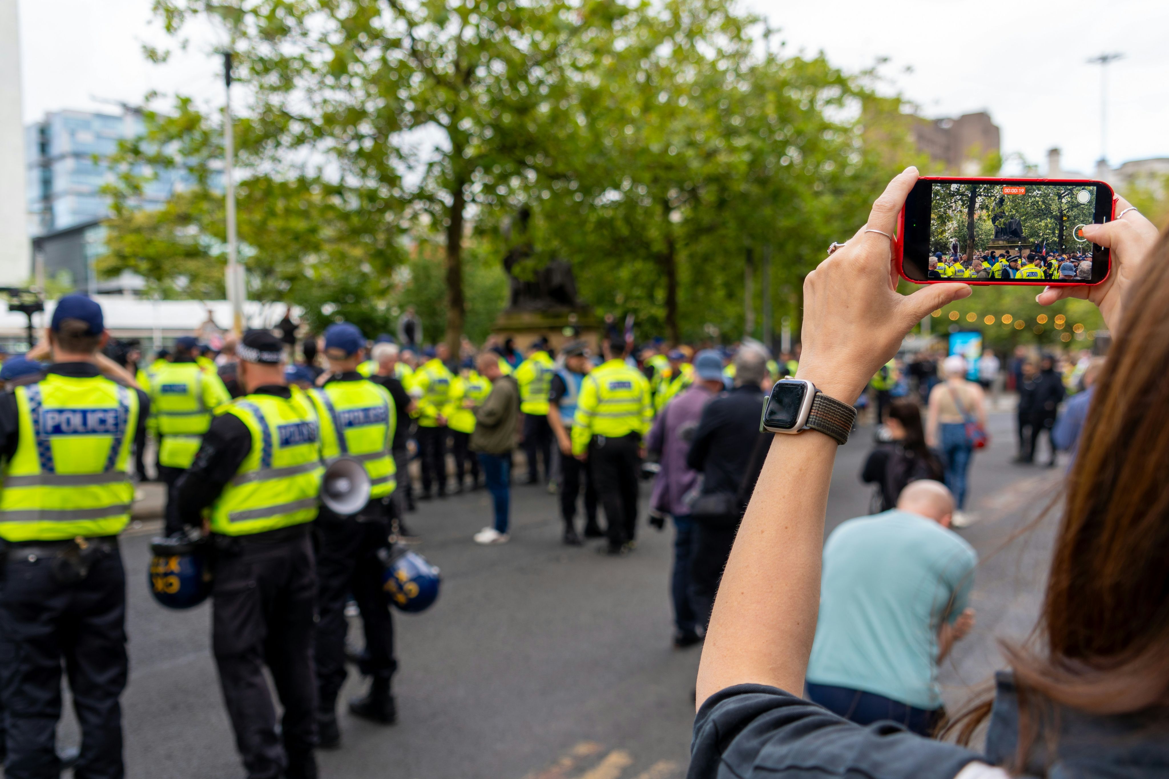 A woman taking a picture of a group of police officers
